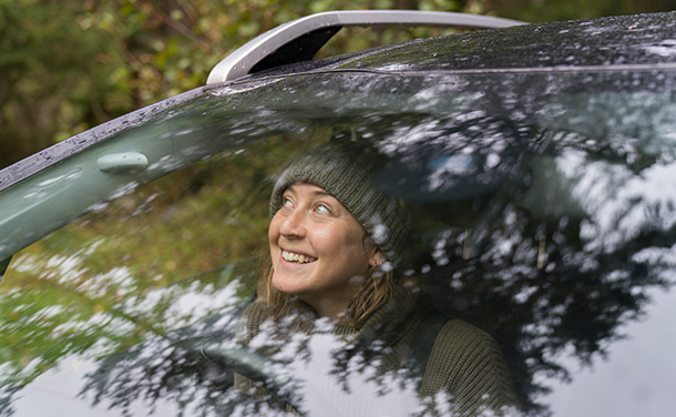 A woman in the front passenger seat of a car looking through the windshield. (photo)