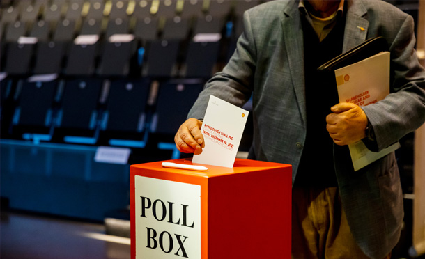 A man putting his vote into a poll box during the General Meeting, December 2021. (photo)
